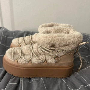 Beiga moon boots från Bershka - Nästan helt nya vinterskor . Säljs då jag ångra mig och instället för att kasta dom är det bättre att det kommer till and vändning hos någon annan! Endast andvänt 4 gånger. Skorna är från Bershka och har beige teddy-matrial. Skorna har även snörning med mönstrae snören och detaljer! Perfekt för kalla dar.  Köpt på Zalando  Själva märket: bershka  Original pris: 700kr (På Zalando) 