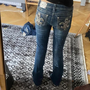 Miss Me jeans - Snygga  jeans från Miss Me med stora broderade fickor bak, dekorerade med silverfärgad fleur-de-lis och glittriga detaljer. Jeansen har bootcut-modell, låg midja och klassisk femficksdesign. Perfekta för dig som gillar statement-jeans med extra detaljer. De är 33 inchees i innerbenslängd vilket motsvarar 83 cm, midjan är ungefär 40 cm rakt över och de är lite stretch💗superbra skick , storlek 29