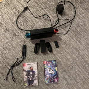 Nintendo Switch med tillbehör och spel - Nintendo Switch i fint skick med original Joy-Con, dockningsstation, laddare, handkontrollhållare, 8BitDo, en USB sticka som gör det möjligt att spela på Nintendot med vilken kontroll som helst ex ps4, och två spel: FIFA 23 Legacy Edition och Just Dance 2022. Allt fungerar som det ska, inga synliga skador eller större slitage. Köpte på Blocket och den var som ny. 