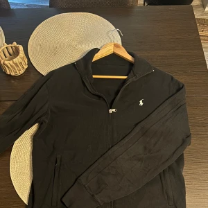 Ralph Lauren full-zip - Ralph Lauren Full-Zip – Snygg och klassisk! Säljer min Ralph Lauren full-zip i riktigt bra skick. Jag är ca 180 cm lång och den är lite oversized på mig, vilket bara ger en härligt avslappnad look utan att det ser slarvigt ut.  Plagget kommer alltid tvättat och struket, redo att användas direkt, och jag skickar inom 1 dag efter köp. En tidlös piece från Ralph Lauren som funkar perfekt till både vardag och mer uppklädda tillfällen!