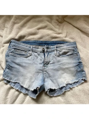 Ljusblå jeansshorts  - Säljer ett par ljusblå jeansshorts från H&M med fransig kant i storlek 34 