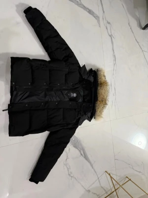 Canada Goose jacka - Säljer en svart dunjacka från Canada Goose med fet pälskant på huvan och klassisk logga på ärmen. Jackan har dragkedja och knappar framtill, samt långärmade ärmar. Perfekt för kalla dagar och riktigt snygg streetstil. StoleL passar där runt M pris ksn nog diskuteras