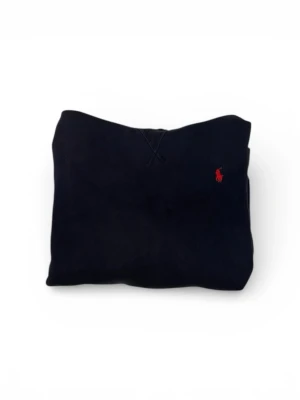 Blå Polo Ralph lauren hoodie  - Mörkblå hoodie från Polo Ralph Lauren i klassisk och tidlös design. Tröjan har huva, känguruficka framtill och den ikoniska röda Polo-loggan broderad på bröstet. Tillverkad i mjukt och bekvämt material med borstad insida som ger extra värme och komfort. Normal passform som passar perfekt till vardagsbruk. Storleken är XL/TG men passar till en kille som är 160 cm lång.