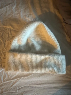 Vit ribbad mössa från Bik Bok - Säljer en vit ribbstickad mössa från Bik Bok med bred uppvikt kant