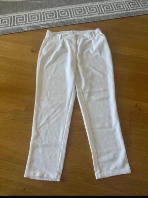 Vita byxor från C, storlek 38 - Säljer ett par vita byxor från C i storlek 38. Byxorna har raka ben, bälteshällor och stängs med knapp och dragkedja. Materialet är frottéliknande och ger en unik känsla. Perfekta för dig som vill ha något stilrent men ändå annorlunda.