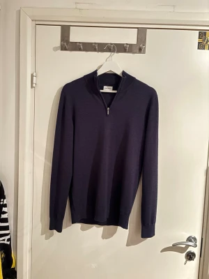 Marinblå half zip tröja John Henric - Säljer en stilren marinblå långärmad tröja från John Henric i storlek S. Tröjan har en snygg half zip-dragkedja vid halsen och är tillverkad i 100% mjuk merinoull. Perfekt för dig som gillar klassisk och enkel design med premiumkänsla.