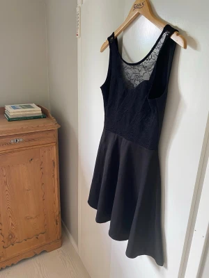 Svart spetsklänning med v-ringning - Aldrig använd, glömts bort i garderoben.. Dock har den av oklara anledningar några hål i spetsen där fram trots att den inte är använd.
