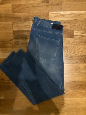 Replay Anbass  - Säljer ett par Replay Anbass jeans i ljusblå tvätt. Klassisk femficksmodell med raka ben och normal passform. Jeansen har snygga slitningar och Replay-lapp bak i midjan. Tillverkade i mjukt jeansmaterial för skön känsla.