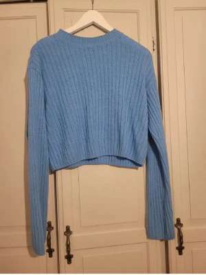 Blå ribbad stickad tröja Gina Tricot - Säljer en ljusblå stickad tröja från Gina Tricot i storlek S. Tröjan är croppad med långärmade, breda ärmar och har ett ribbat mönster som ger en snygg struktur. Perfekt för dig som gillar en chill och trendig look.