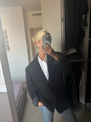 Oversized svart kavaj - Säljer en oversized svart kavaj med klassisk krage och knäppning framtill. Kavajen har långa ärmar och tre knappar vid ärmslutet. Perfekt för en chill och stilren look, funkar lika bra till jeans som till kostymbyxor.