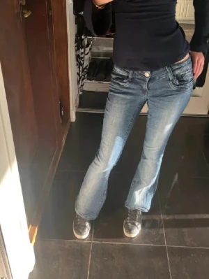 Blå bootcut jeans med låg midja - Säljer ett par snygga blå jeans med bootcut och är low waist för att jag behöver spara pengar för tillfället! De är dessutom lite kortare än vad jag brukar gilla på mig🥰 dom är i topp skick och använda typ 3 gånger 