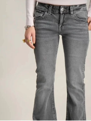 Grå bootcut jeans från Gina tricot  - Snygga grå jeans från Gina tricot med bootcut-snitt och broderade detaljer på bakfickorna. Jeansen är i superfint skick, använda ett fåtal gånger. 