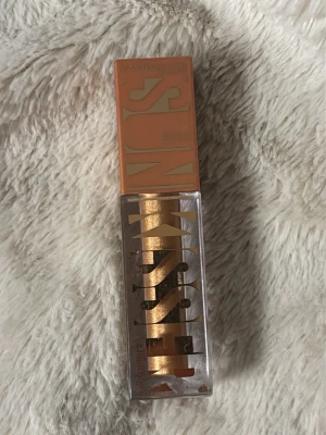 Maybelline  Electric Bronze - Flytande bronzer från Maybelline i färgen 11 Electric Bronze. Kommer i en fyrkantig plastförpackning med applikator. Skimrande bronzig nyans som ger en metallisk finish. Perfekt för att skapa en glittrig look med intensiv färg. I väldigt bra skick, använd bara en gång