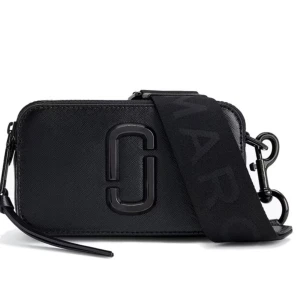 Svart axelväska från Marc Jacobs - Snygg svart axelväska från Marc Jacobs med stilren design och bred axelrem med logga. Väskan har en rektangulär form, dragkedja upptill och är tillverkad i skinn med en diskret struktur. Perfekt för att bära det viktigaste med stil. Prislappen är borta annars oanvända!