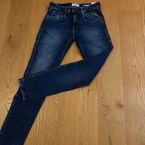 Helt nya! Replay Anbass jeans mörkblå skinny - Snygga Replay Anbass jeans i mörkblå tvätt med skinny passform. Klassisk femficksdesign, gul kontrastsöm på bakfickorna och dragkedja i gylfen. Perfekta för dig som gillar en smal siluett och stilren look.