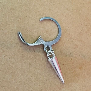 By prisförslag- 1 st Silvrigt örhänge med konformad hängande detalj - Coolt örhänge i silverfärgad metall med en hängande konformad spets. Ringen har en enkel klickstängning och den minimalistiska designen ger en edgy vibe. Perfekt för dig som gillar att sticka ut med dina accessoarer.