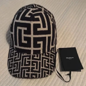 Balmain Paris - Snygg keps från Balmain köpt från NK. Aldrig använd. Skick: 10/10. Nypris: 4 449kr. Väldigt snygg och unik keps! 