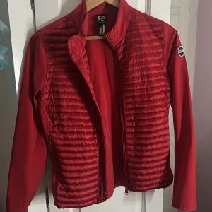 Röd pufferjacka från Colmar - Snygg röd pufferjacka från Colmar med quiltade paneler framtill och slät rygg. Jackan har lång ärm, hög krage och dragkedja. Materialet är glansigt och känns lätt, perfekt för dig som vill ha en sportig och modern look. Colmar-logga på ärmen och bak. Skit snygg jacka som jag gillar att använd‼️ använt den 3 gånger och sitter jättefint på kroppen, säljs ENDAST för den inte kommer till användning ‼️☺️