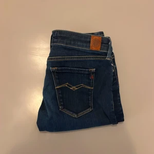 Replay Hyperflex jeans blå, stl 28 - Säljer ett par mörkblå Replay Hyperflex slim fit jeans med snygga kontrastsömmar och klassisk femficksdesign. Jeansen har stretchigt material för extra komfort och en modern passform. Märkesdetaljer på fickor och midja. Perfekta för dig som gillar stilrena och bekväma jeans. 28/30
