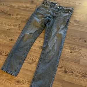Ljus Blå jeans från Jack & Jones straight fit - Snygga ljus blåa jeans från Jack & Jones med rak passform. Jeansen har normal midja, knappgylf och läderpatch bak. Tillverkade i slitstarkt denimtyg som ger en cool och tidlös look.
