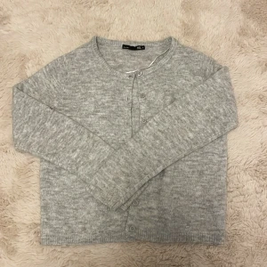 Grå kofta från Lager 157 - En simpel grå kofta från Lager 157 i storlek XS, mjuk och bekväm. Den är använd men finns inga tecken på skador eller liknande. Kontakta gärna vid intresse, frågor eller annat, vid köp välj gärna Instabox eller Postnord, det blir lättare för mig att frakta! 