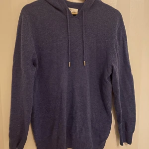 hoodie i kashmir från Garde Grisch - Mysig blå hoodie från Garde Grisch i mjuk merinoull. Tröjan har huva med snörning. Perfekt för dig som gillar chill och stilren look. Väldigt skön och få använd. Ställ gärna frågor angående om pris eller annat, svarar oftast snabbt