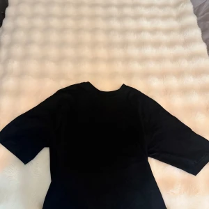 Svart t-shirt från 157, storlek S - Använd en gång! Svart t-shirt från 157 i storlek S. Klassisk rund hals och korta ärmar, perfekt enkel stil. Den går ut vid magen, så inte rak. 