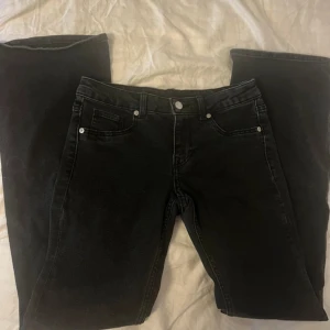 Svarta jeans från H&M Divided, strl 40 - Svarta jeans från H&M Divided i klassisk femficksmodell. Jeansen har raka ben och normal passform, tillverkade i bomullsmix med lite stretch för extra komfort. Perfekta till sneakers eller boots och funkar året runt.