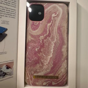 Ideal of Sweden mobilskal - Stilrent mobilskal med marmormönster i rosa och guld, designat för iPhone 11/XR. Skalets tunna och lätta konstruktion ger ett elegant utseende och skydd mot repor. Kompatibelt med trådlös laddning. Skicket är nytt och förpackningen är intakt.