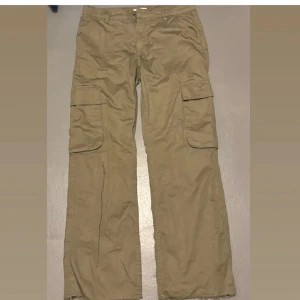 Beige/grön cargobyxor GinaTricot - Beige/grön beiga cargobyxor från Gina med breda ben och stora fickor på sidorna. Perfekta för en avslappnad och trendig look.