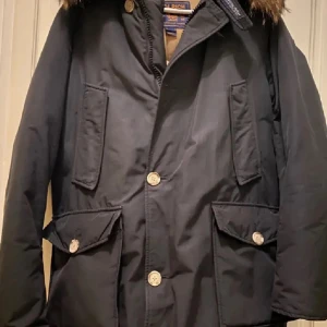 Woolrich Arctic Parka  - Woolrich Arctic Parka Herr  Storlek: M.  Färg: Svart Köpt i Woolrich butiken, kvitto finns!  Jackan säljs, pga att jag köpt en annan jacka. Jackan är använd men finns inga defekter alls! Passar både M och L 