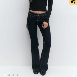 Svarta bootcut jeans med kontrastsömmar - Snygga svarta jeans med bootcut passform och vita kontrastsömmar. Låg midja och klassisk femficksdesign. Perfekta för dig som vill ha en trendig och stilren look.