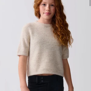 Beige stickad kortärmad tröja - Supermjuk och enkel beige stickad tröja med korta ärmar och rund hals. Perfekt för lager-på-lager och chill vibes. Den har en rak passform och ribbad kant vid halsen för en clean look. . förlåt för dåliga bilder hör av er om ni vill ha fler elr bättre bilde