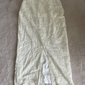 Vit lång spetskjol med slits - Säljer min vita/smutsvita spetskjol som jag inte använt. Slitsen är framtil och på mig som är 163 cm lång går den till lite över anklarna. 