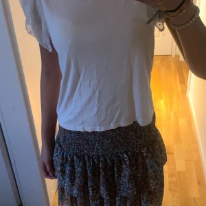 Vit blus med volangärmar från Amisu - Supersöt vit blus från Amisu i storlek XS. Toppen har korta, transparenta volangärmar med spetsdetaljer och diskret prickigt mönster. Kroppen är i mjuk bomull och ärmarna i tunnare material som ger en romantisk vibe. Perfekt för dig som gillar feminina detaljer. Längd 47 cm bred 40 cm