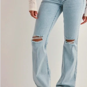 Ljusblå bootcut jeans med slitningar - Snygga ljusblå jeans med bootcut passform och slitna detaljer vid knäna. Jeansen har klassisk femficksdesign och är tillverkade i denim. Från Nelly.com har dessa i storlek( 34) kom privat för bilder 