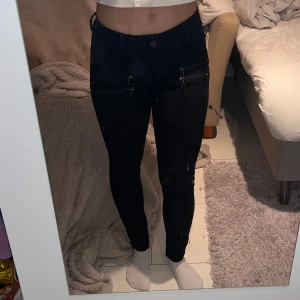 Svarta skinny jeans med dragkedjor - Svarta skinny jeans från Denim 1953 i modellen 'elsa'. Byxorna har hög midja och flera snygga dragkedjor framtill som ger en cool detalj. Tillverkade i stretchigt jeanstyg för en tight och bekväm passform. Perfekta för dig som gillar en stilren men edgy look.