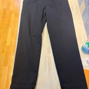 Marinblå byxor från Dickies - Säljer ett par marinblå kostymbyxor från Dickies med klassisk rak passform(slim straight . Byxorna har diskreta fickor och är tillverkade i ett slitstarkt material som känns både stilrent och bekvämt. Perfekta för dig som gillar en clean och tidlös look.