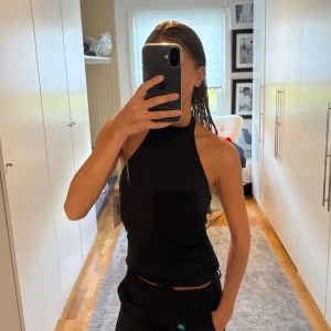 Svart halterneck linnetopp - Säljer en svart halterneck linnetopp med hög hals och öppen rygg. 