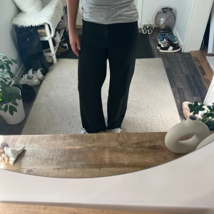 Svarta vida jeans - Säljer ett par svarta jeans med hög midja och rak, vid passform. Byxorna har klassisk look och är perfekta för en stilren outfit. Materialet känns mjukt och följsamt, vilket gör dem bekväma att bära hela dagen.