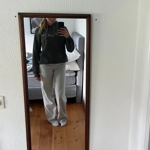 Grå hoodie från Tommy Hilfiger - Säljer en grå hoodie från Tommy Hilfiger med vit logga och broderad detalj framtill. Perfekt för dig som gillar en clean och klassisk streetstil.