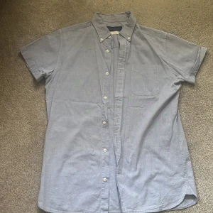 Ljusblå kortärmad skjorta Jack & Jones - Snygg ljusblå skjorta från Jack & Jones med korta ärmar, klassisk krage och bröstficka. Skjortan har knappar hela vägen och är gjord i mjuk bomull, perfekt för en clean och avslappnad look. Stl L