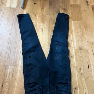 Replay Anbass  - Svarta Replay Anbass jeans i slim fit med slitna detaljer och lagningar på benen. Nästan helt nya!