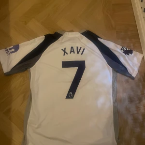 Tottenham Hotspur hemmatröja Xavi Simons 7 Nike tröja - Säljer en Tottenham Hotspur fotbollströja från Nike med Xavi och nummer 7 på ryggen. Tröjan är vit med mörkblå och grå detaljer. Den är helt oanvänd och i nytt skick. Den funkar både som M och L