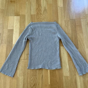 Beige långärmad topp med vågmönster -  långärmad topp med vågigt mönster och lätt utsvängda ärmar. Tunn och stretchig, perfekt att styla med jeans eller kjol. Ger en cool och trendig vibe till din outfit.