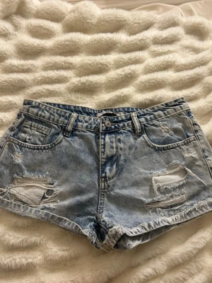 Ljusblå jeansshorts - Säljer sjukt snygga jeansshorts med slitningar. Storlek EU38