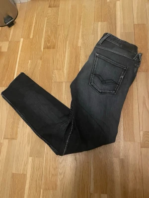 Svarta Replay jeans med raka ben - Snygga svartgråa jeans från Replay med klassisk femficksdesign och raka ben. Jeansen har diskreta slitningar och tydliga sömmar, vilket ger en cool och modern look. Perfekta för dig som gillar stilrena och bekväma jeans i jeansmaterial. Jeansen är i storlek w34 l34, men jag tycker att de passar w33 l31