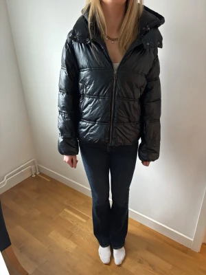 Svart pufferjacka från Massimo Dutti, M - Snygg svart pufferjacka i lite glansigt material och med stor huva och quiltad design. Perfekt för kalla dagar när du vill hålla värmen. Storlek M. Mycket bra skick.