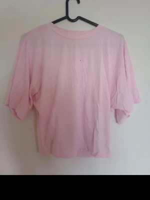 Ljusrosa t-shirt från 157 - Enkel och stilren ljusrosa t-shirt från 157 med rund halsringning och korta ärmar. Tillverkad i mjuk bomull som känns skön mot huden. Perfekt basplagg att matcha med jeans eller kjol för en avslappnad look.