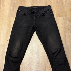 Svarta jeans från Nudie Jeans - Snygga svarta jeans från Nudie! Jeansen är i väldigt bra skick och är perfekta för en stilren look nu till vintern/våren. De är i storlek W34. Mitt pris:699kr! (Ej hugget i sten) Tveka inte på att ställa frågor!